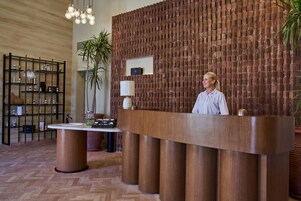 A reception desk with a wooden finish, a potted plant, and a modern light fixture.