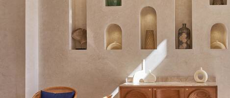 A room with a rattan chair, a round table, and a wooden cabinet with multiple compartments.