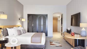A modern hotel room with a large bed, bedside tables, a desk, and a TV.