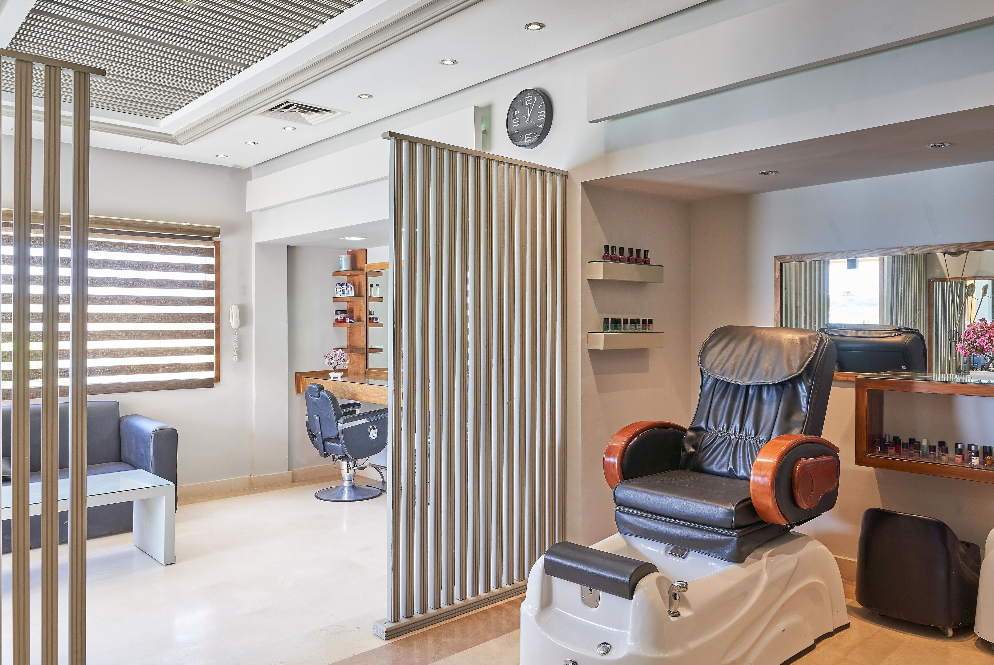 Ein moderner Spa-Raum mit Massagesessel, Glastisch und Sitzgelegenheit.