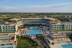 Un hotel moderno con piscina central, varios balcones y un patio ajardinado.