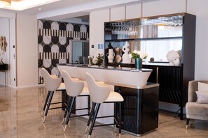 Una cocina moderna con una isla central, taburetes de bar y una zona de comedor con sofá.