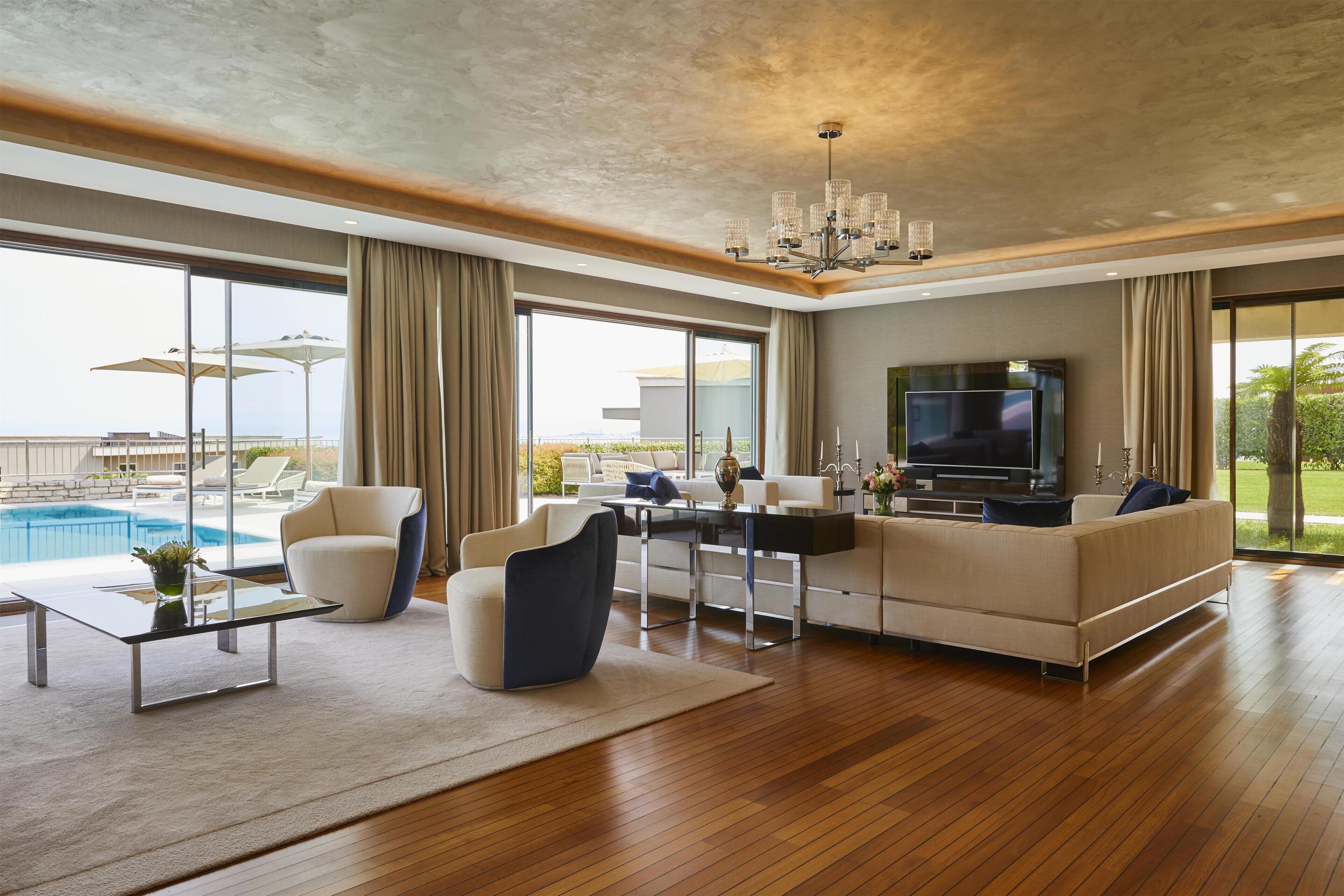 Una sala de estar moderna con televisor grande, asientos cómodos, vista a la piscina y un balcón amplio.