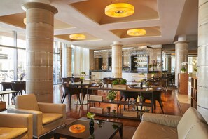 A spacious lobby with high ceilings, large pillars, and a central bar area. There are seating arrangements and a variety of plants. - Adriatic Istria Resort Operated by Minor Hotels (Umag)