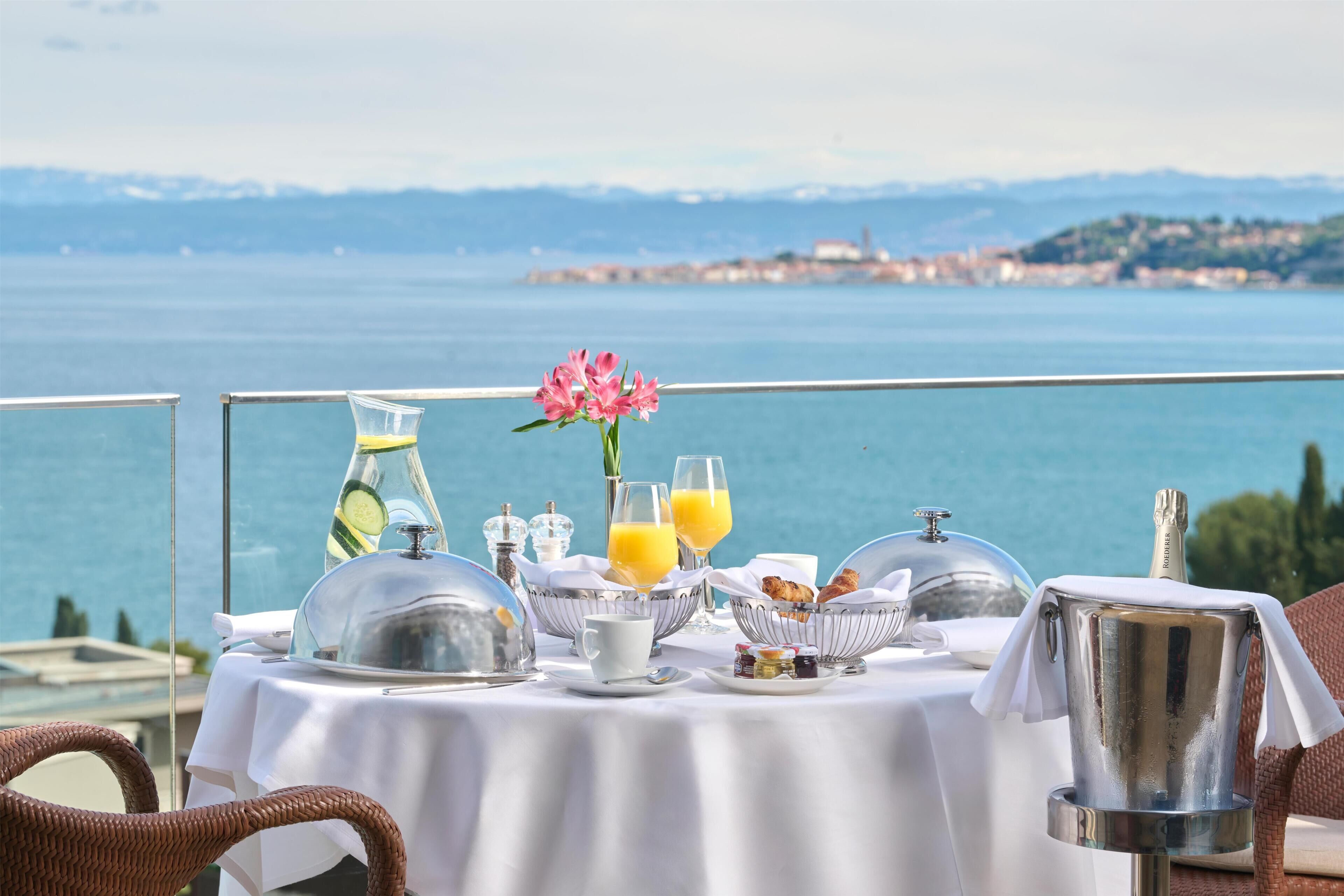 A table set for breakfast with a view of the sea and mountains.