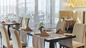 Een restaurant met gedekte tafels, met een uitzicht door grote ramen.