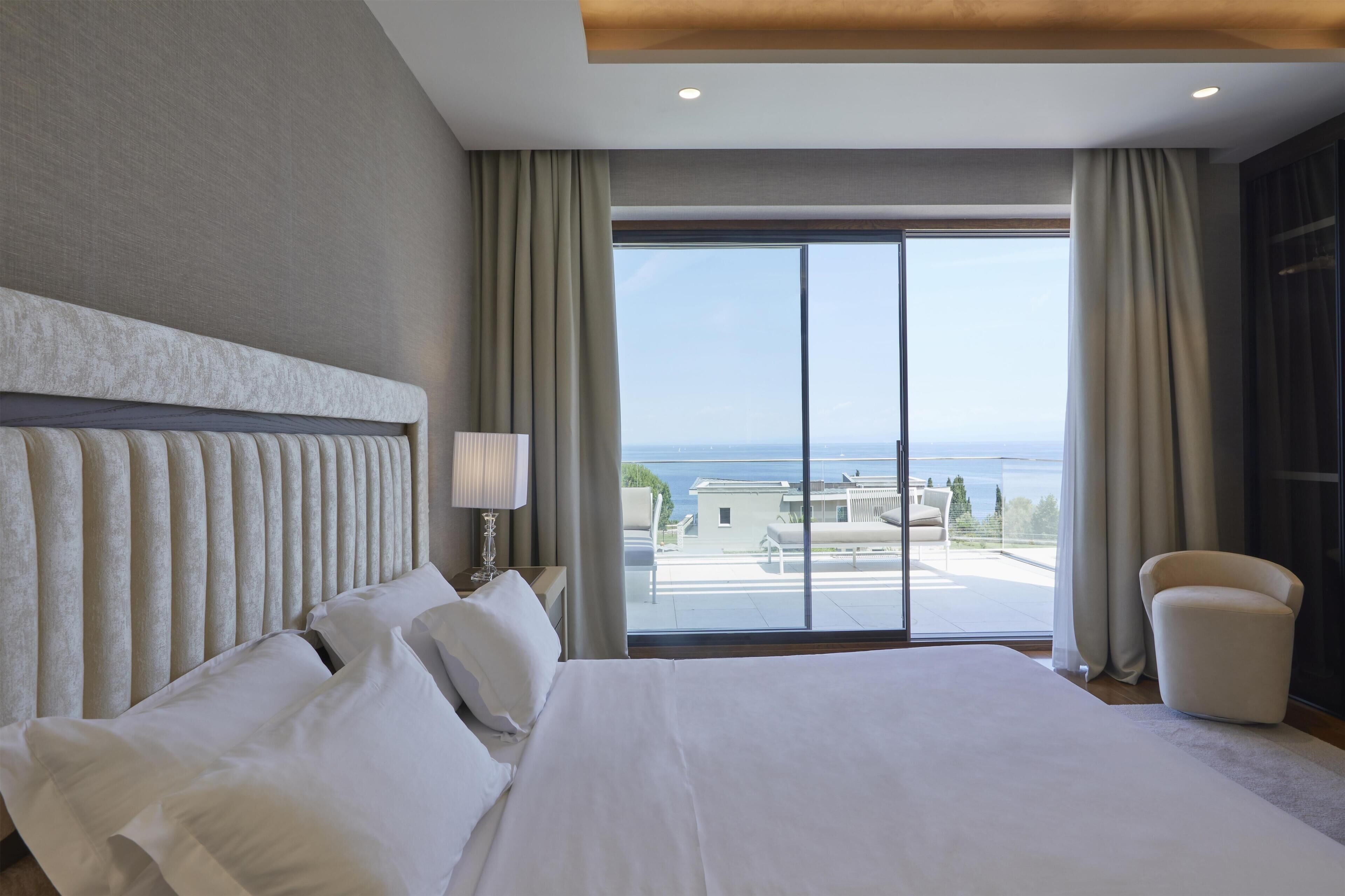A hotel room with a large bed, a view of the sea, and a balcony.