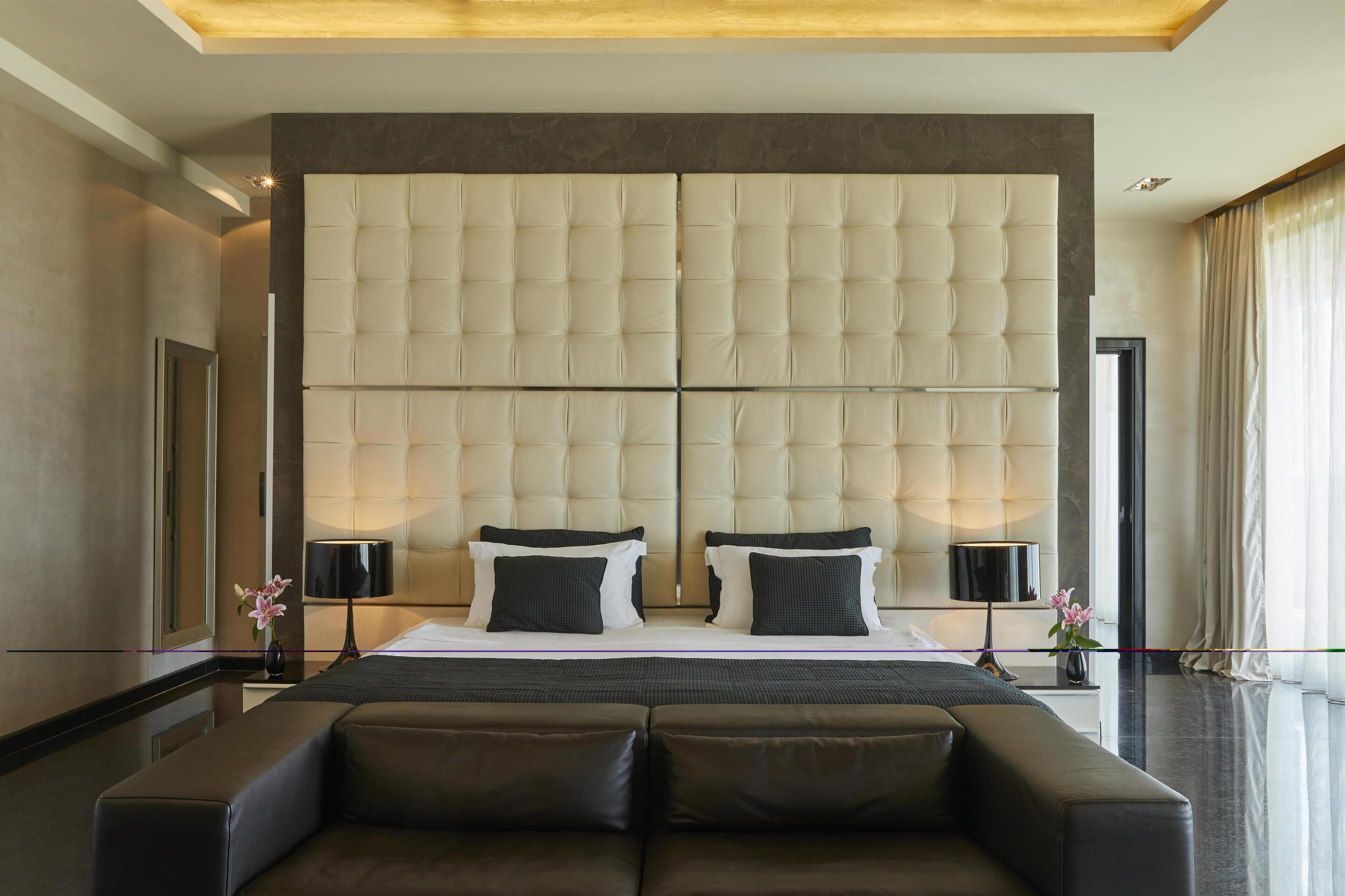 A modern hotel room with a large bed, two bedside tables, and a sofa.