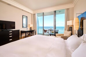 A hotel room with a large bed, a desk with a chair, a television, and a view of the sea through large windows. - Adriatic Istria Resort Operated by Minor Hotels (Umag)