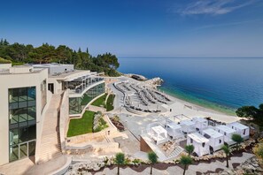 Un hotel moderno frente al mar, con piscina, zona de estar al aire libre y vistas panorámicas.