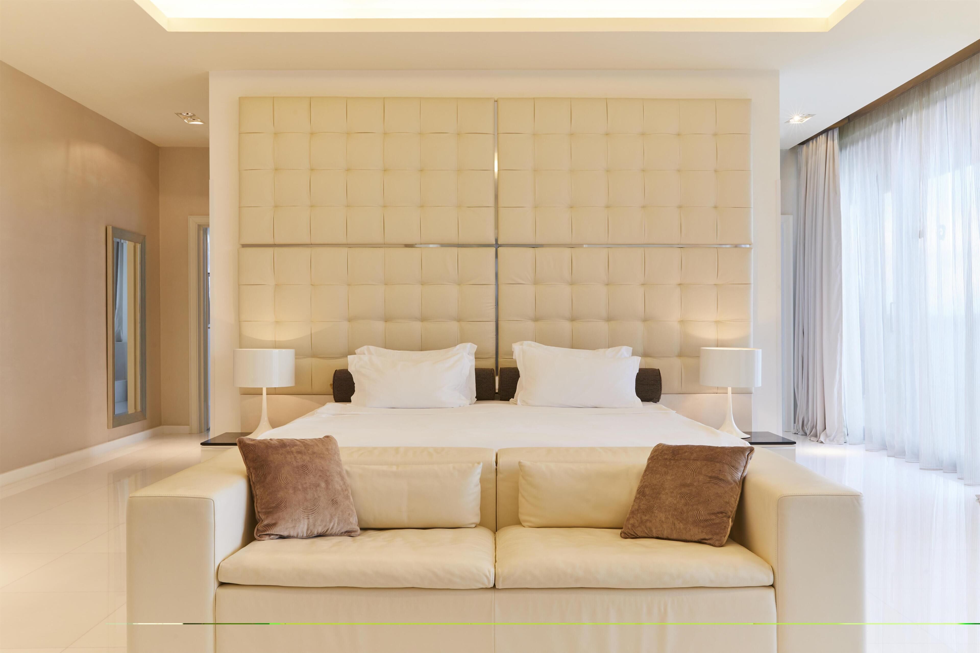 A modern hotel room with a large bed, two bedside tables, and a sofa.