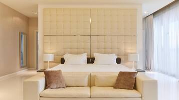 Une chambre d’hôtel moderne avec un grand lit, deux tables de chevet et un canapé.