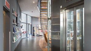 Un interior moderno con una escalera curva, estanterías y un vidrio que da a otra zona.