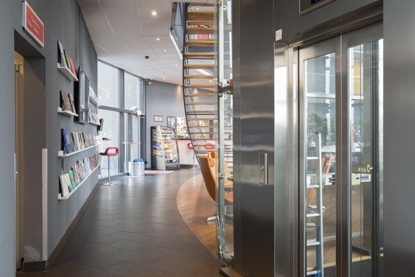 Un intérieur moderne avec un escalier à volutes, des étagères et une porte vitrée donnant sur un autre espace.