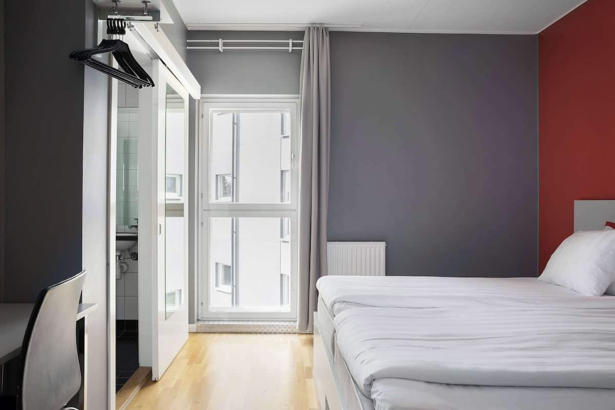 A bedroom with a bed, a desk, and a wardrobe.
