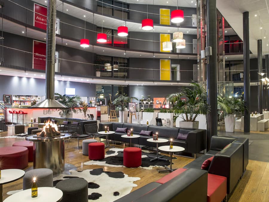A multi-level indoor space with seating areas, tables, and a central fire feature.