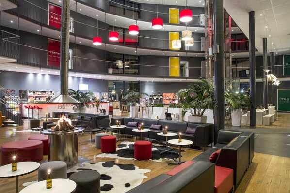 A multi-level indoor space with seating areas, tables, and a central fire feature.