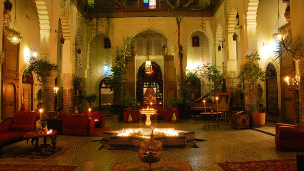 A luxurious interior with a central fountain, red sofas, and ornate decor.