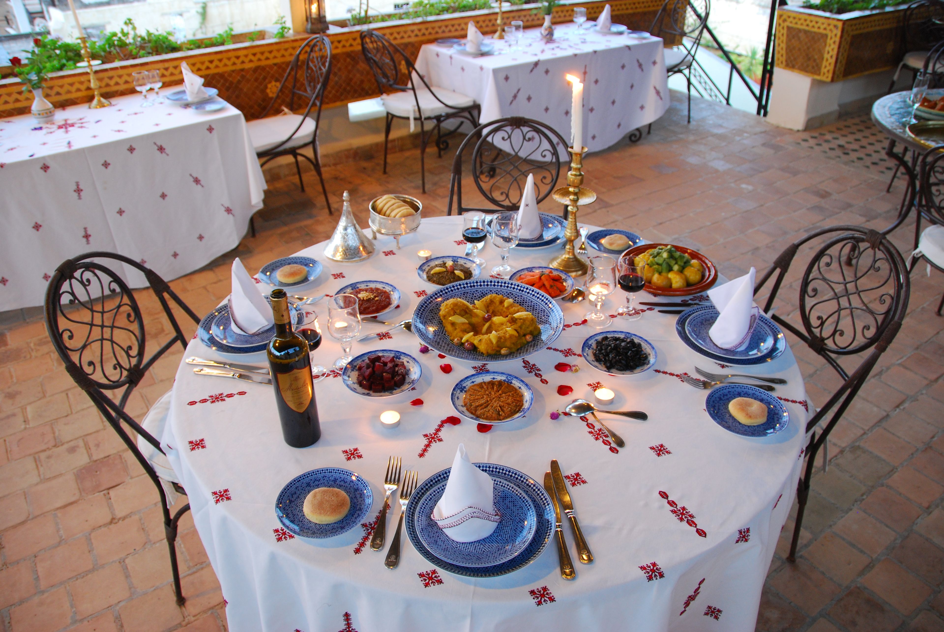 Mesa posta para refeição, com diversos pratos, talheres e uma garrafa de vinho.