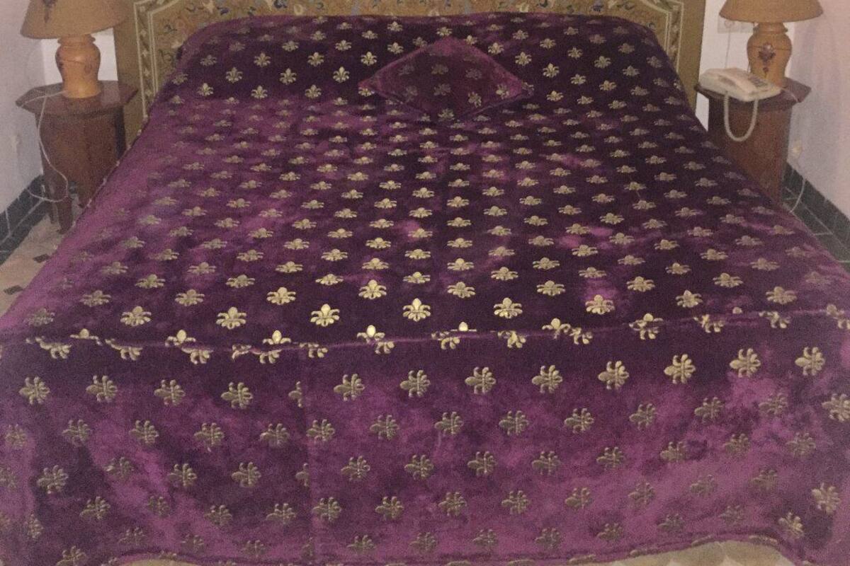 A bed with a patterned headboard and a purple bedspread.