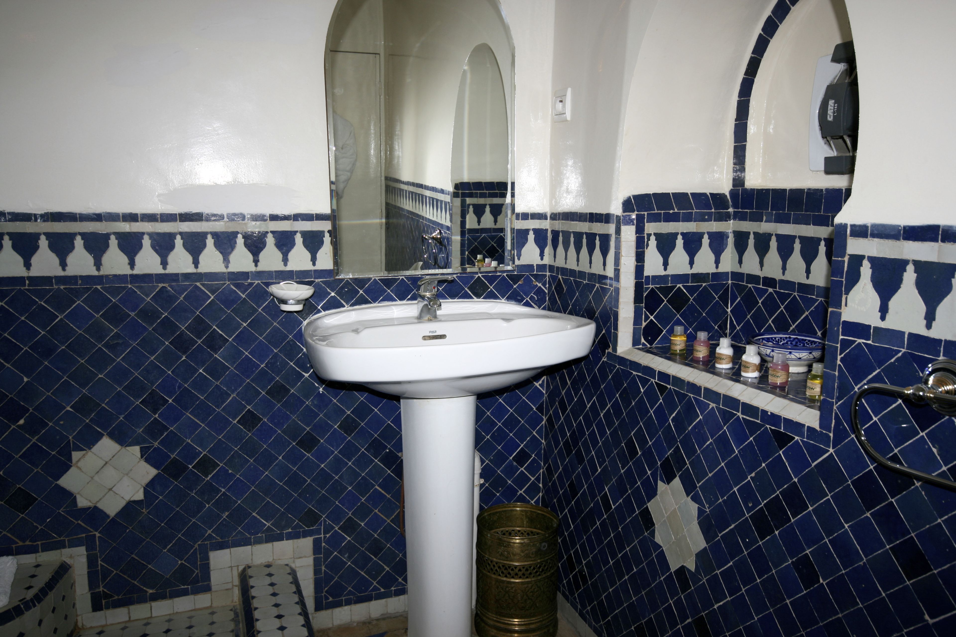 A bathroom with a white sink, blue and white patterned tiles, and a mirror above the sink.