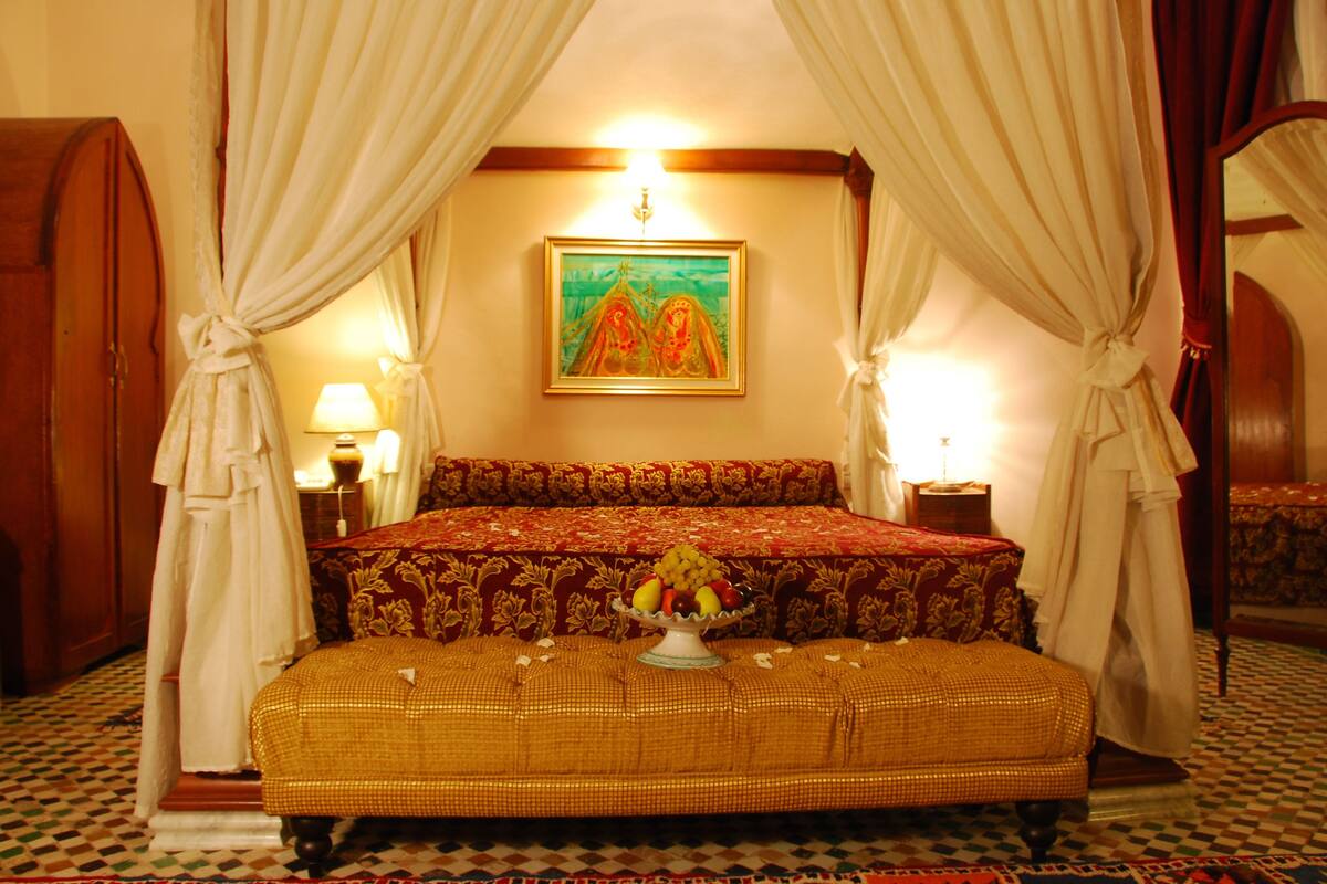 A traditional room with a bed, a fruit bowl, and a painting on the wall.