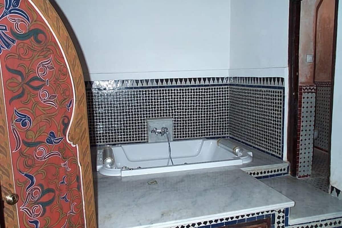 A bathroom with a bathtub, tiled walls, and a patterned door.