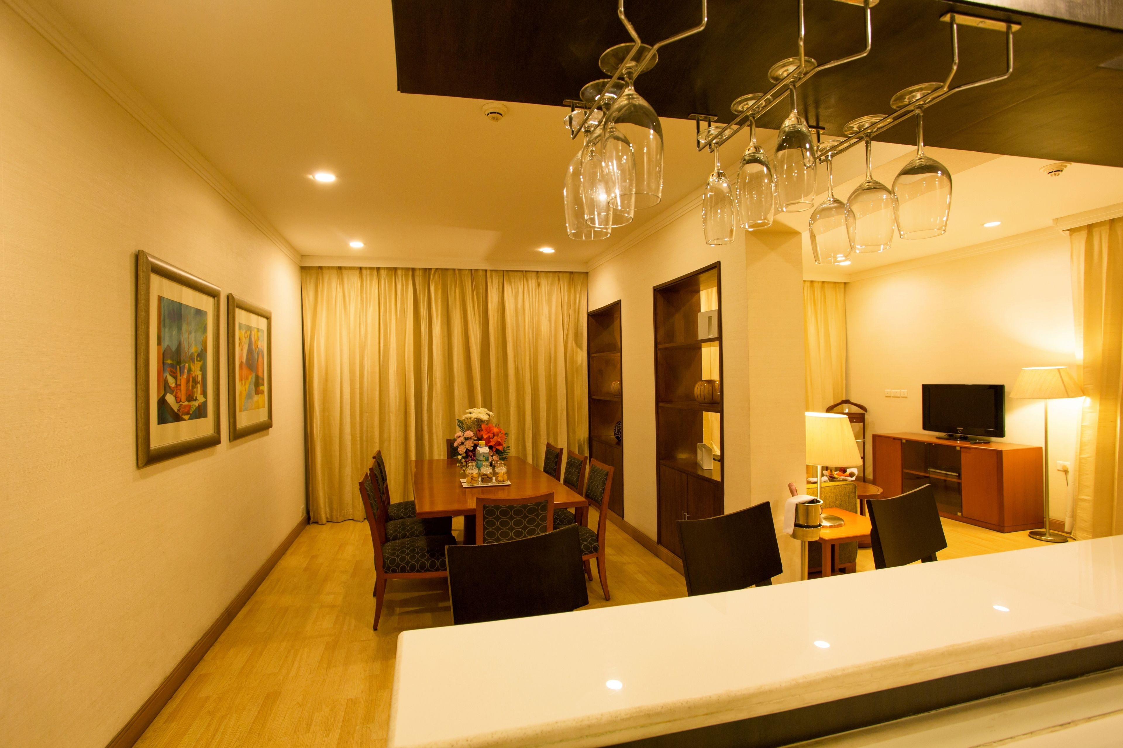 Habitación de hotel con comedor, televisión y lámpara.