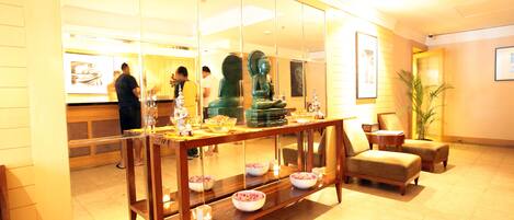 A lobby with a reception desk, seating area, and a Buddha statue.