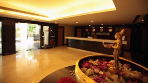 A reception area with a reception desk, a statue, and a flower arrangement. - Ellaa Hotel Gachibowli (Hyderabad)