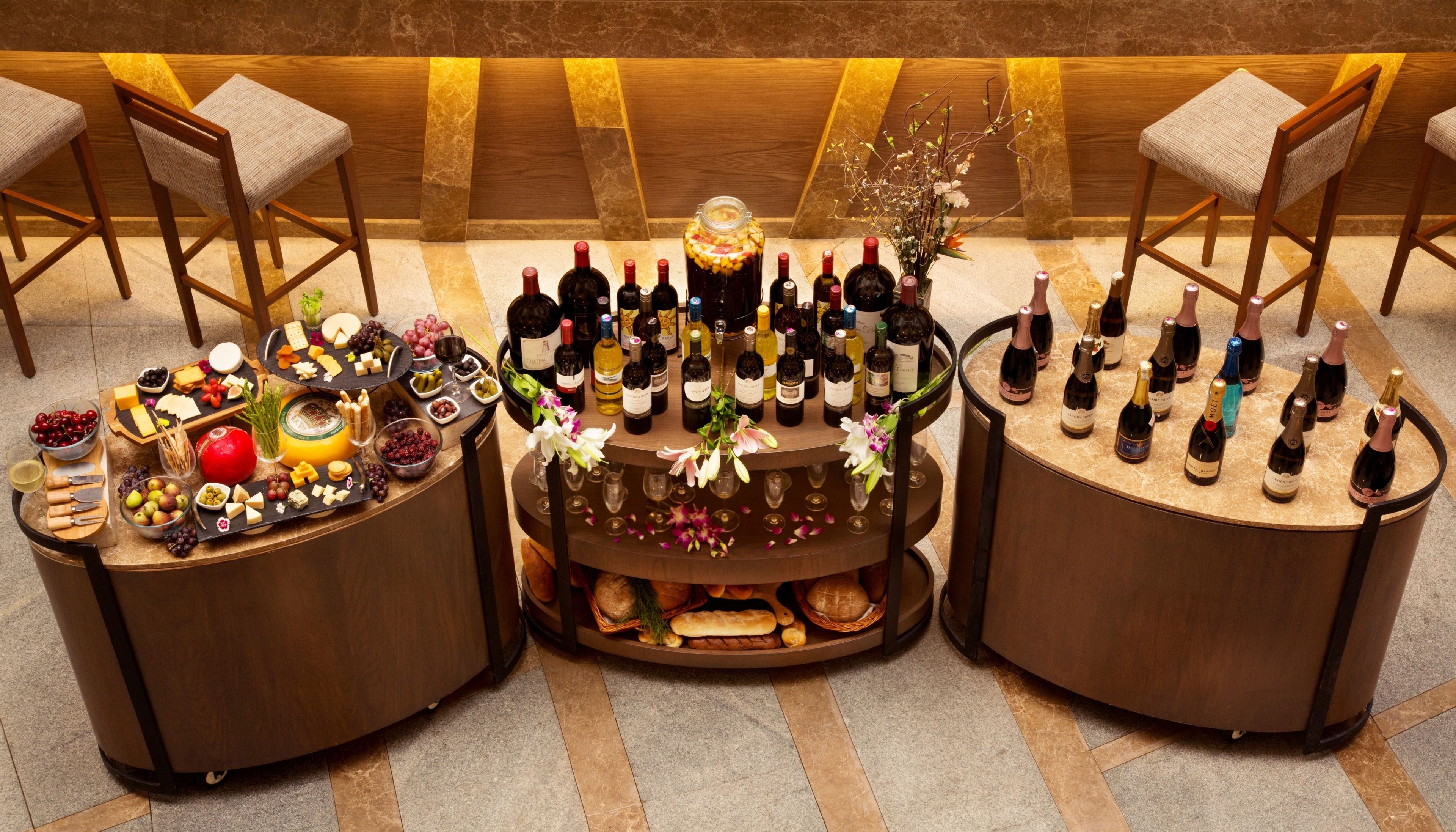 Una barra bien surtida con varias botellas de vino y licores, una selección de quesos, frutas y pan.