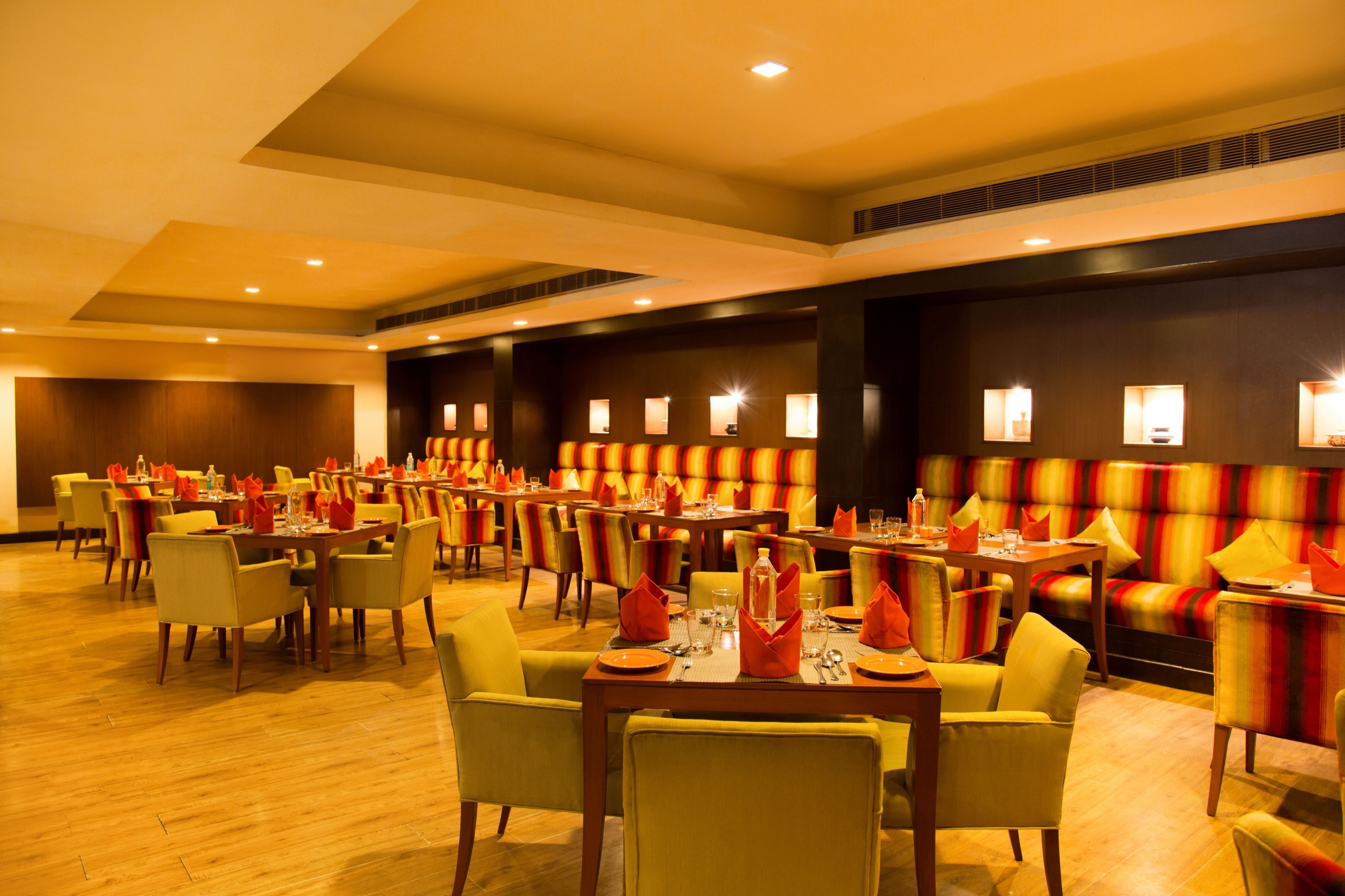 A spacious dining area with multiple tables and chairs, arranged in a modern, well-lit setting.