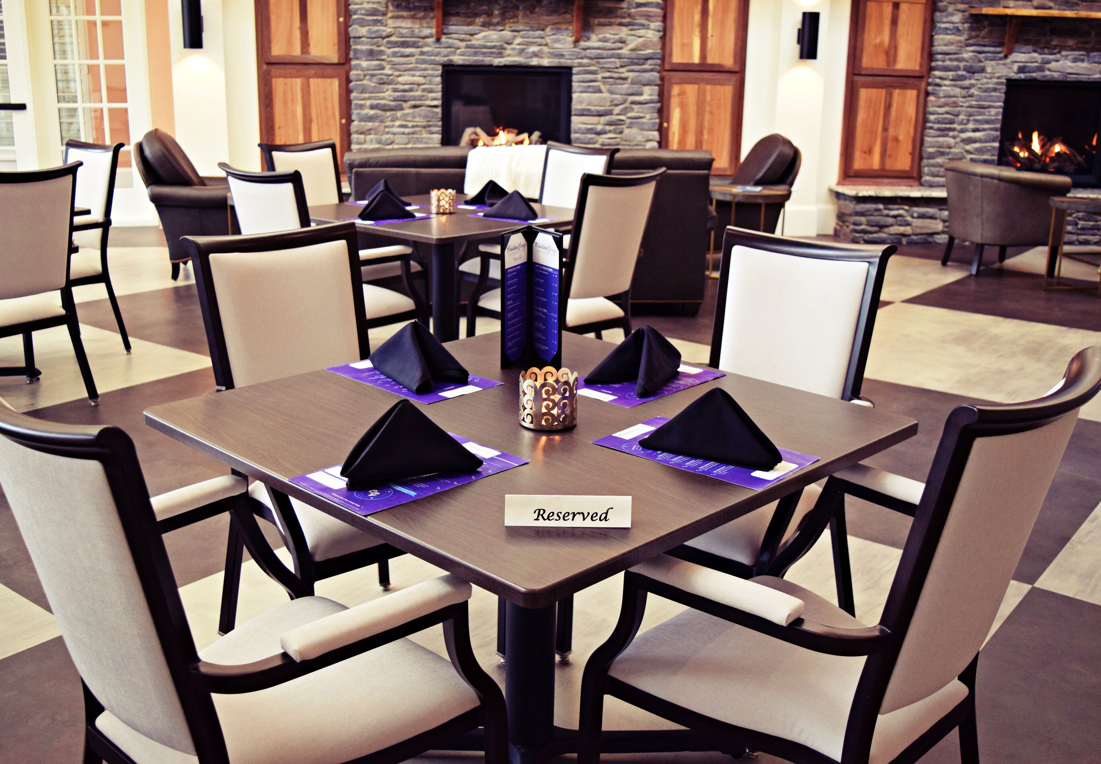 A dining area with tables set for four, each with a 'Reserved' sign, chairs, and a decorative vase.