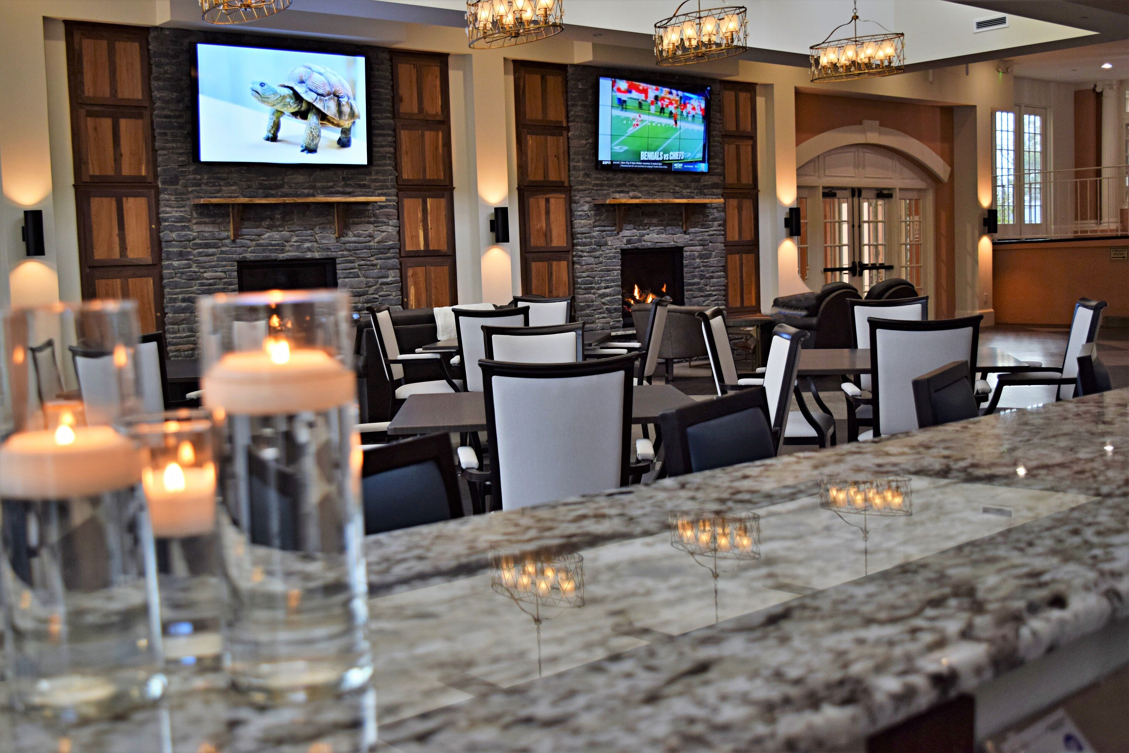 A restaurant with a stone fireplace, multiple TVs, and candle-lit tables.