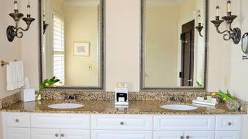 Un bagno con due lavabi, un mobile contenitore con cassetti, uno specchio grande, applique e un quadro appeso alla parete.