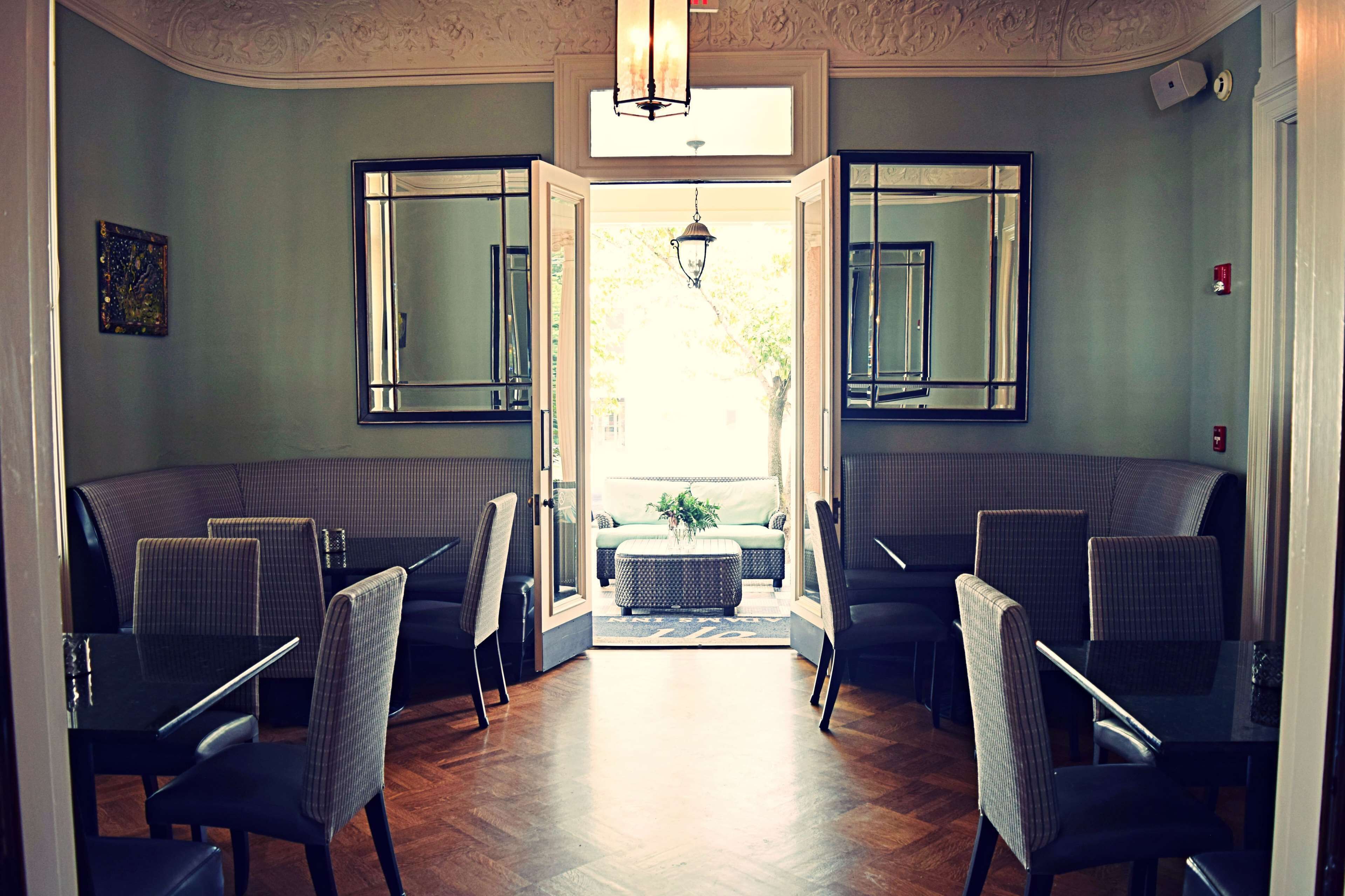 A room with a seating area featuring cushioned benches and chairs, a central ottoman, and a large window providing a view of the outdoors.