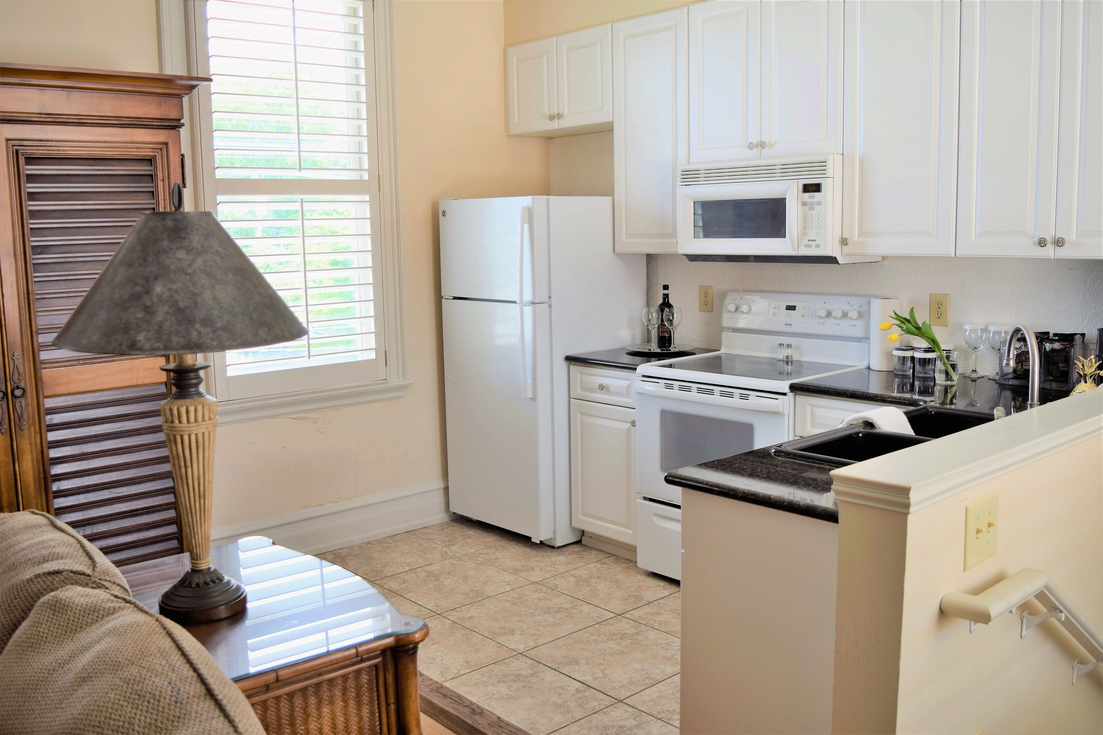 A kitchen with white cabinets, a refrigerator, a microwave, an oven, and a sink.