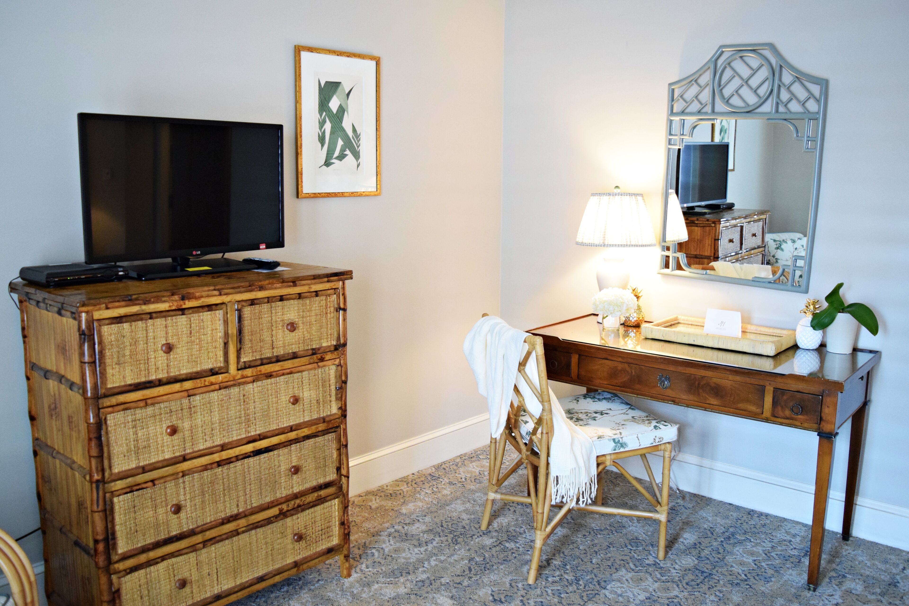 Une pièce comprenant une commode en bois, un bureau avec un miroir, une chaise et un téléviseur.