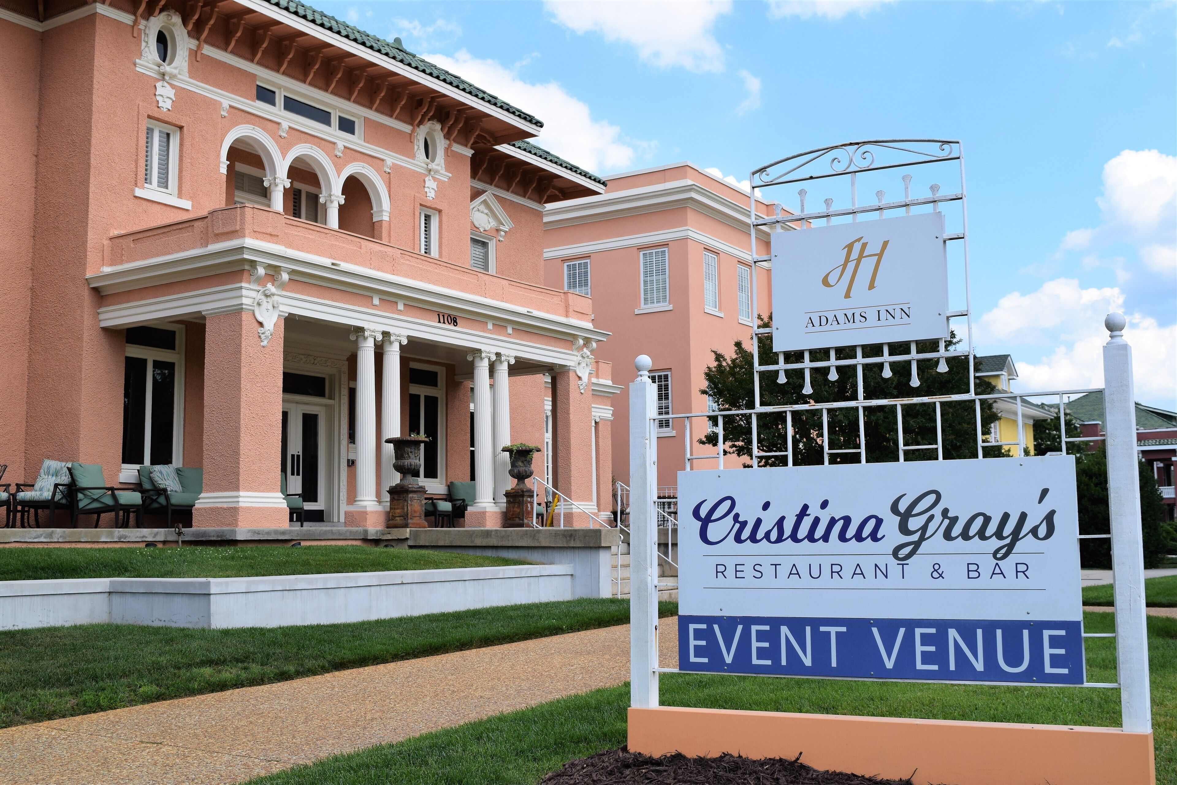 Un edificio con un cartel que anuncia 'Cristina Gray's Restaurant & Bar' y 'Adams Inn', con un estilo arquitectónico clásico.
