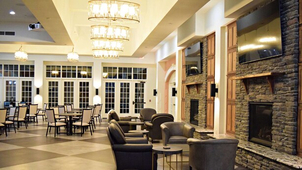 A spacious lobby with a checkered floor, leather sofas, and a stone fireplace. - JH Adams Inn, Trademark Collection by Wyndham (High Point)