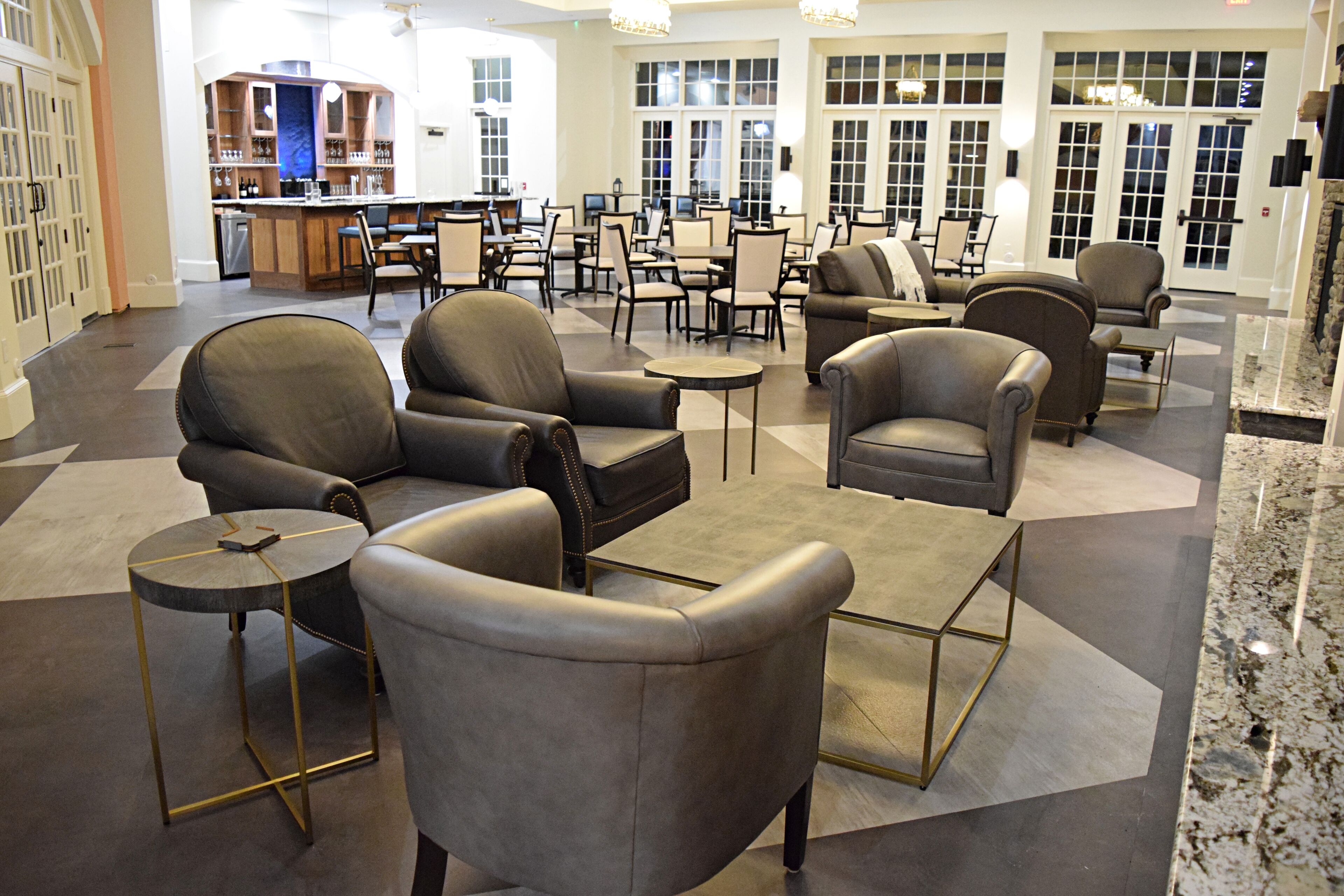A spacious lobby with leather armchairs, a bar area, and a seating area with tables and chairs.