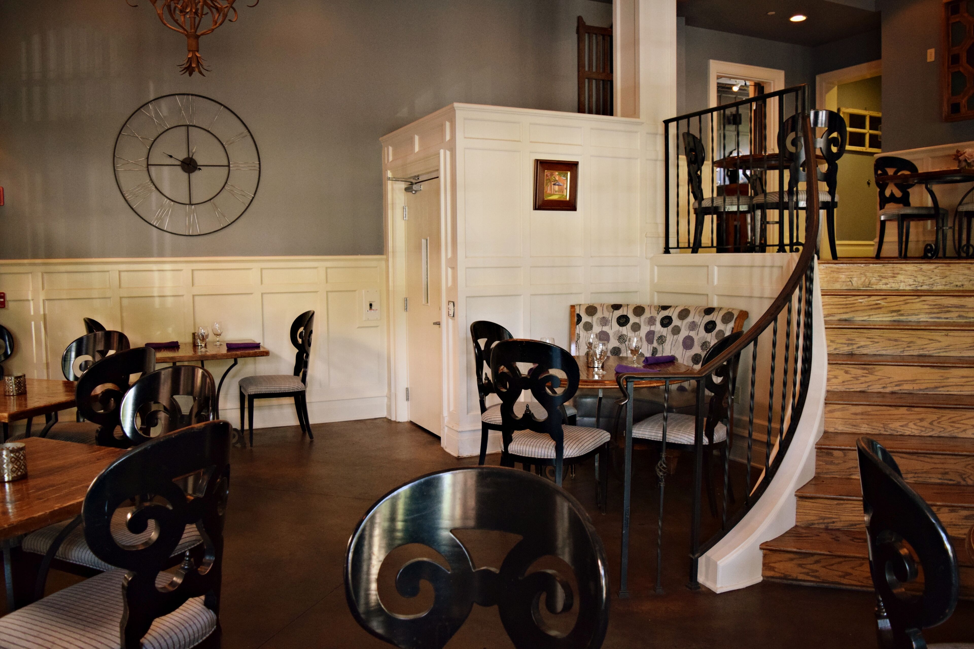 A dining area with a round table, chairs, and a staircase leading to an upper level.