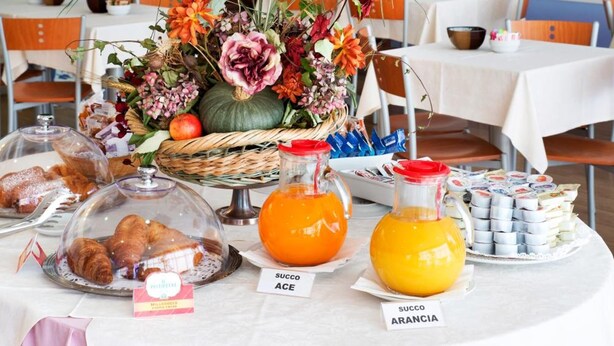 A breakfast buffet with various food items, including pastries, fruits, and beverages, set up on a table with a decorative hanging floral arrangement above. - Hotel Master (Turin)