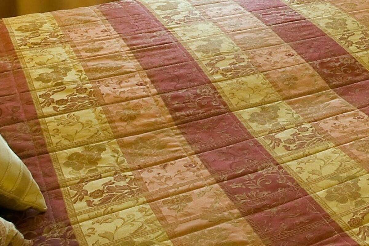 A bed with a floral patterned quilt and two pillows.