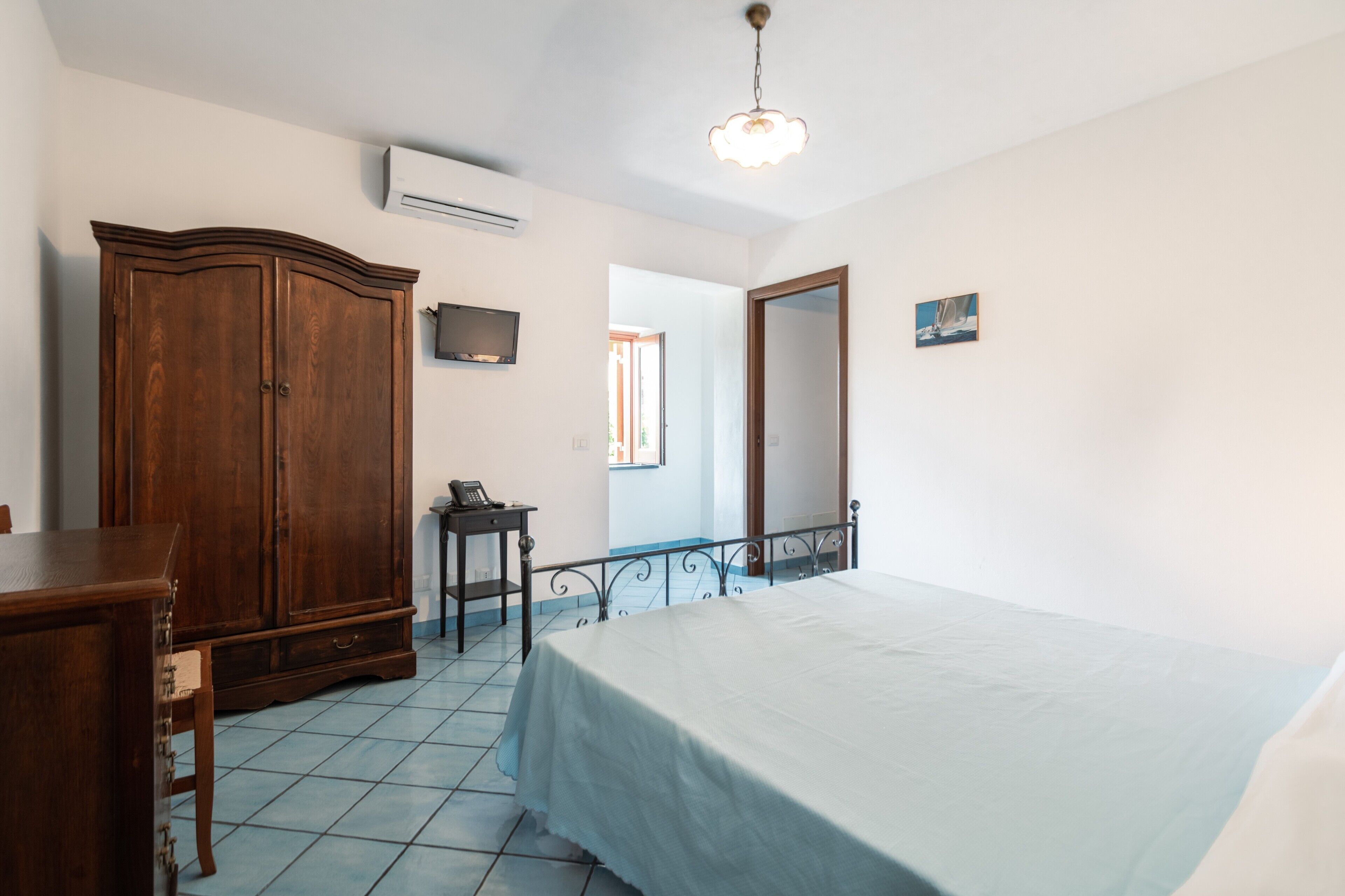 Ein Schlafzimmer mit Bett, Kleiderschrank und einem kleinen Tisch mit Telefon.