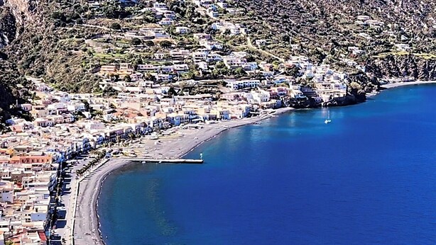 A coastal town with a curved coastline, a marina, and buildings along the shore.