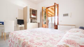 A bedroom with a bed, a desk, a TV, and a wardrobe.