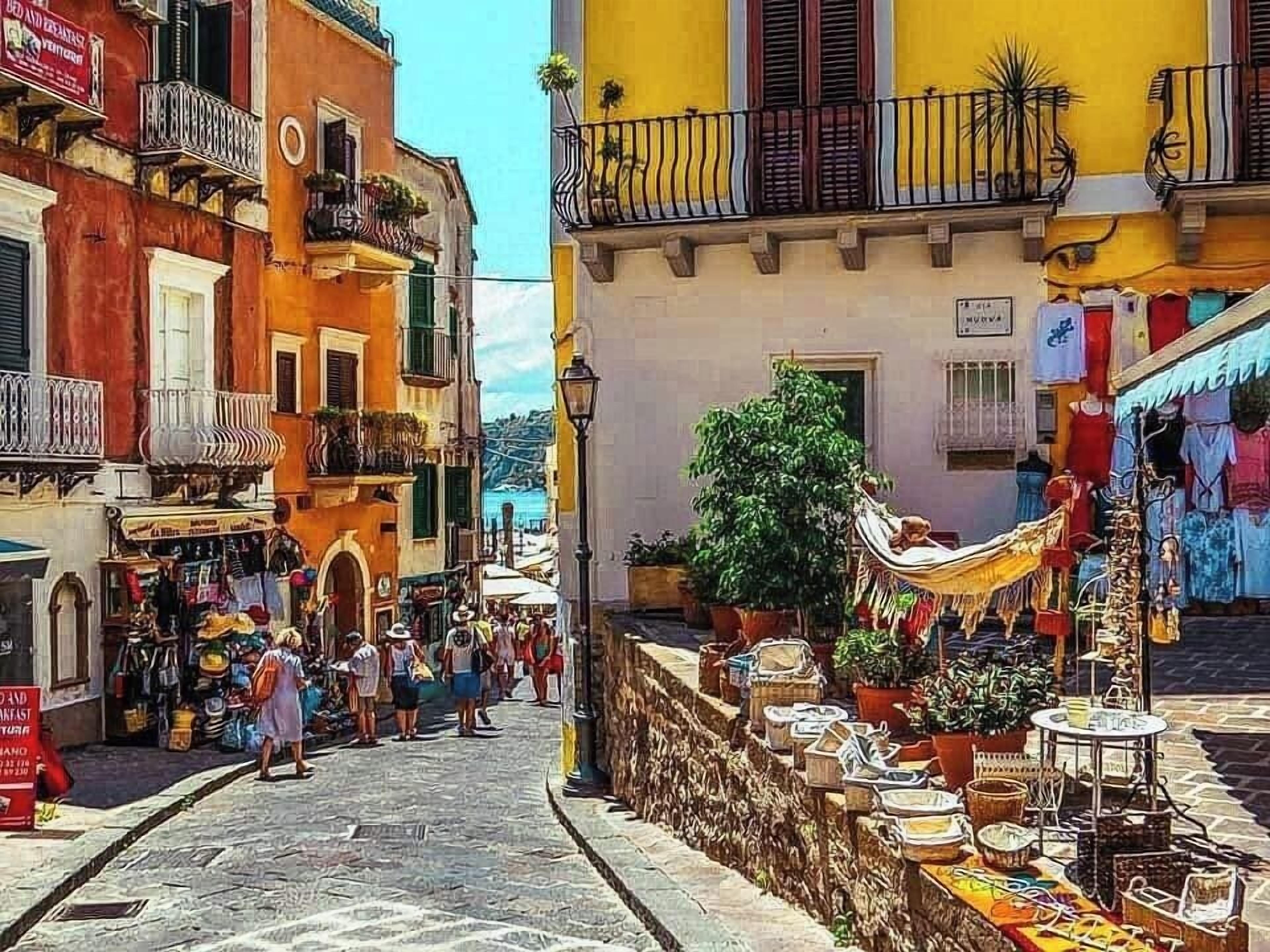 Une rue étroite bordée de bâtiments des deux côtés, avec des terrasses et une variété de boutiques.