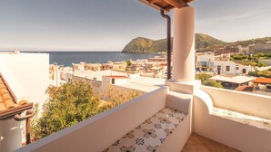 A balcony with a view of the sea and a hillside.