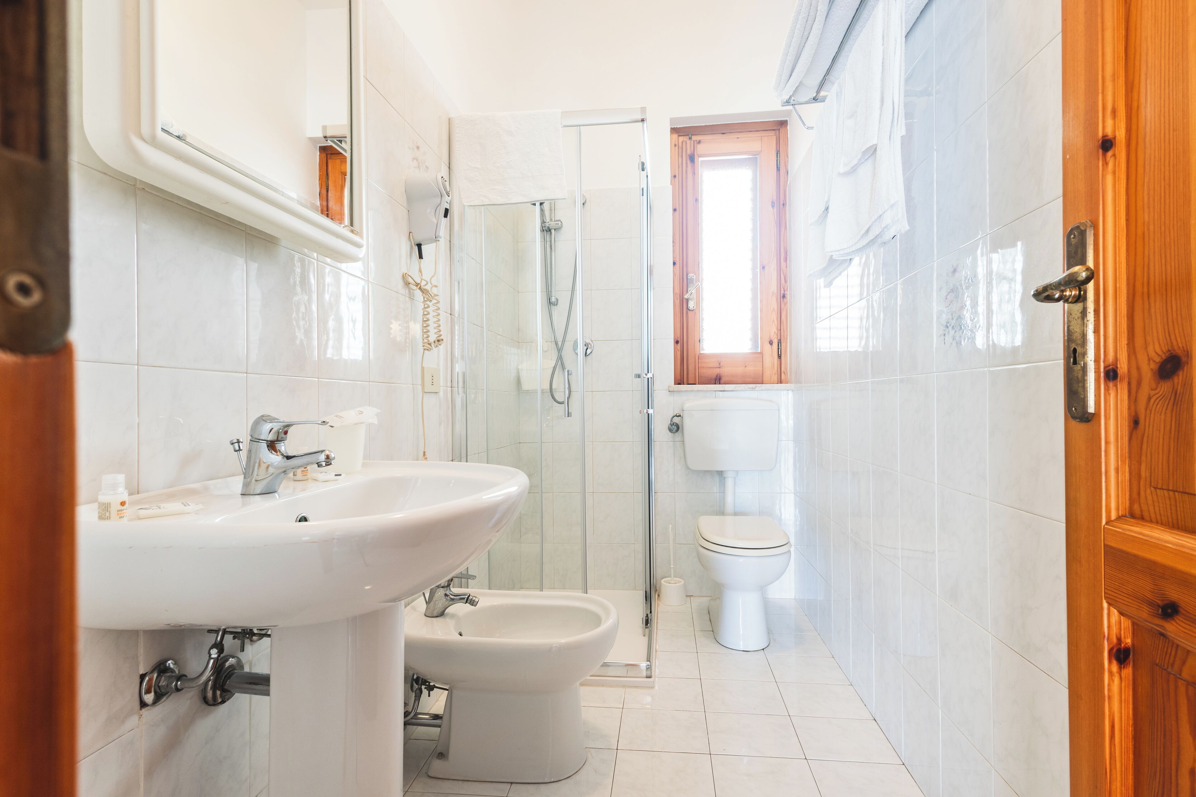 A bathroom with a sink, bidet, toilet, and glass shower enclosure.